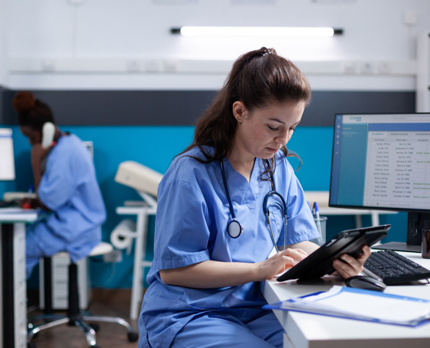 Nurse Using A Tablet Near Computer